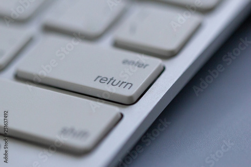 Wireless keyboard on gray background. Which is a close-up angle focusing on the Return or Enter button
