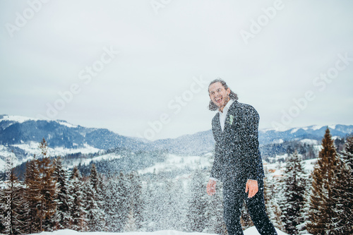 Happy man in a suit throws snow up