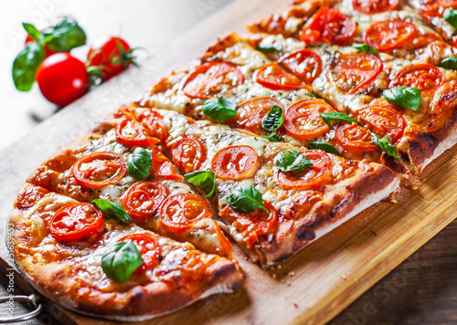 oval Pizza with Mozzarella cheese, Tomatoes, pepper, Spices and Fresh Basil. Italian pizza. Pizza Margherita or Margarita on wooden table background