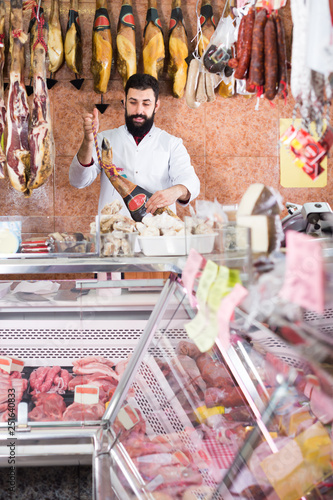 Young male seller showing jamon