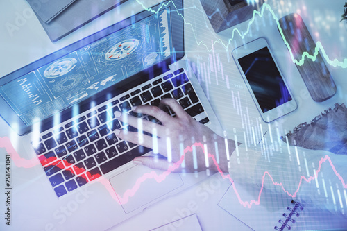 Hands typing on laptop. Business and Financial concept. Double exposure of stock market charts.