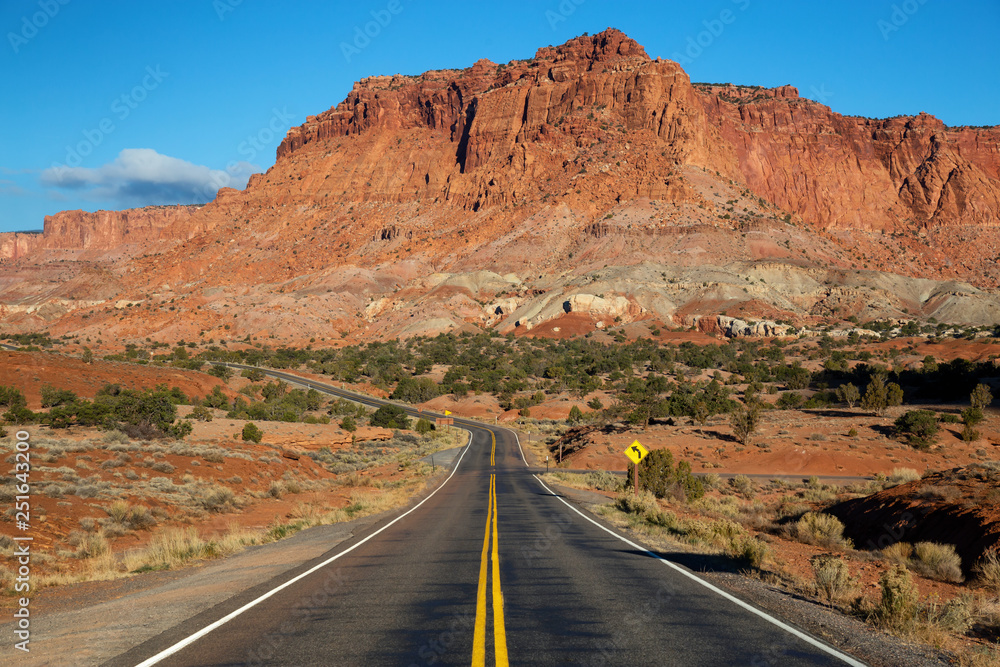 Scenic road in the desert during a vibrant sunny sunrise. Taken on Route 24 near Torrey, Utah, United States of America.