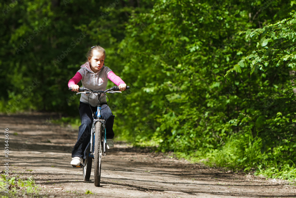Naklejka premium Girl on a bike in the forest