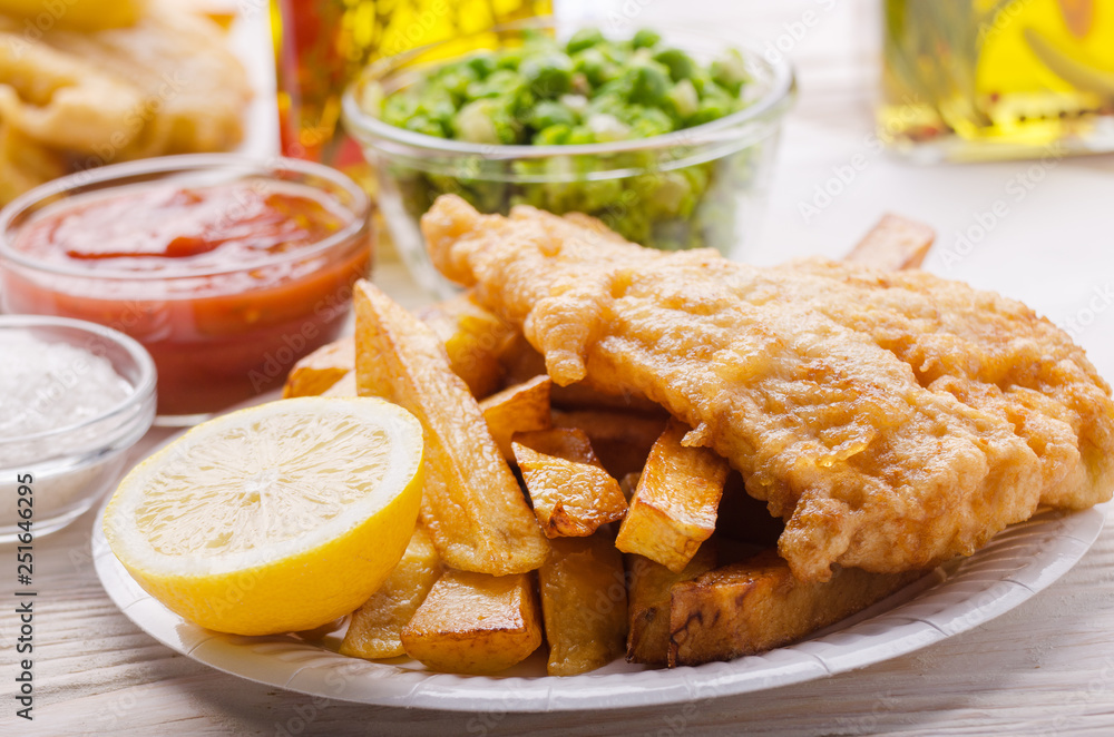 Traditional British street food fish and chips with ketchup sauce and mushy peas on paper plate Traditional British street food fish and chips with ketchup sauce and mushy peas on paper plate