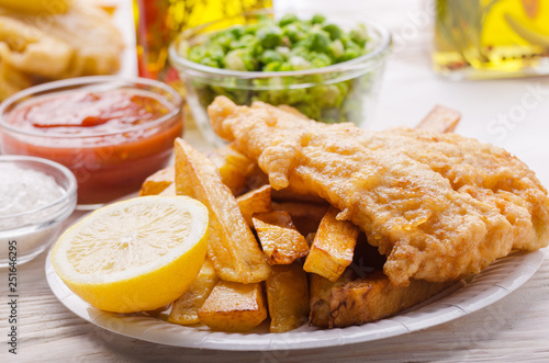 Traditional British street food fish and chips with ketchup sauce and mushy peas on paper plate