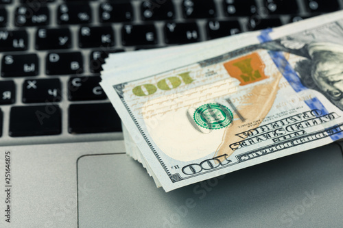 Closeup view of one hundred dollar banknotes lying on the laptop keyboard © Nana_studio