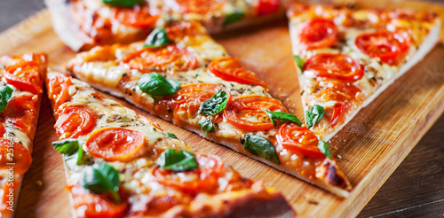 Pizza with Mozzarella cheese, Tomatoes, pepper, Spices and Fresh Basil. Italian pizza. Pizza Margherita or Margarita on wooden table background