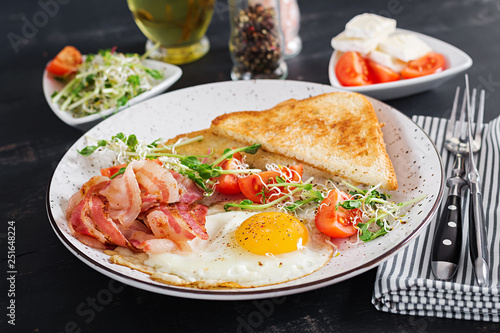 English breakfast - toast, egg, bacon and tomatoes and microgreens salad.