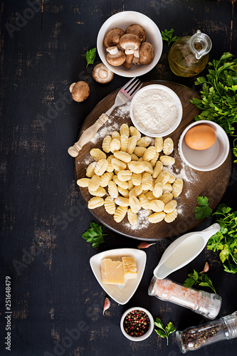 Uncooked homemade Gnocchi with a mushroom cream sauce and parsley in bowl on a dark background. Top view