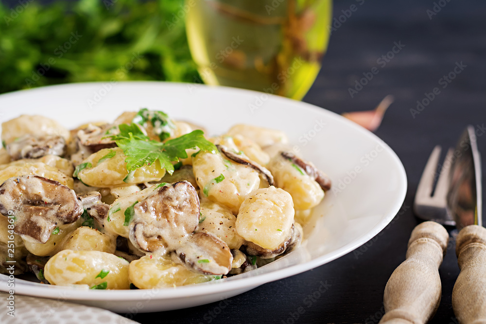 Gnocchi with a mushroom cream sauce and parsley  in bowl on a dark background