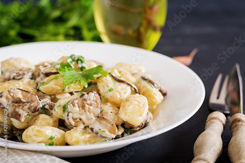 Gnocchi with a mushroom cream sauce and parsley  in bowl on a dark background