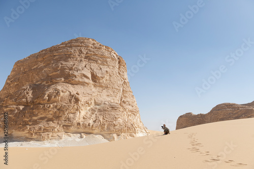 Female tourist taking photos on a sanddune in the El Aqabat desert in the White Desert National Park