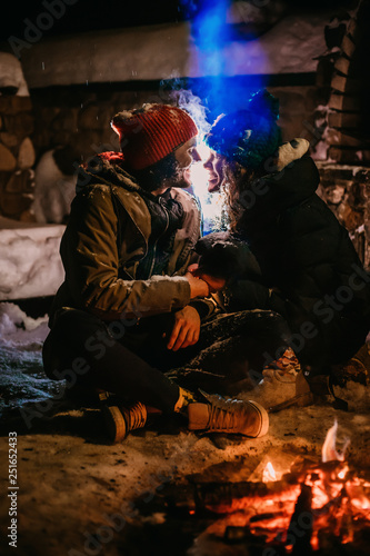 Sweet couple in colored hats sitting near the fire.