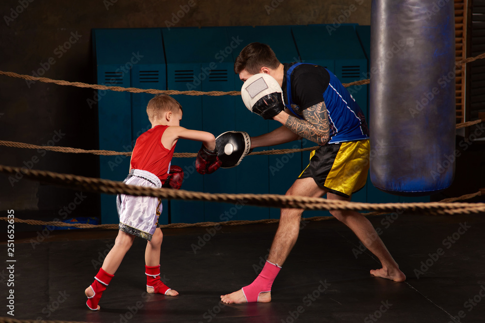 Trainer teaching a kid how to hit punches. Kid wearing boxing gloves