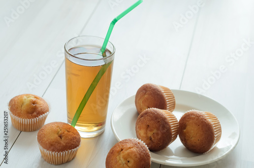 A glass of Apple grapefruit juice, three muffins on a plate and more three sweet muffins ..Fresh breakfast on the morning. photo