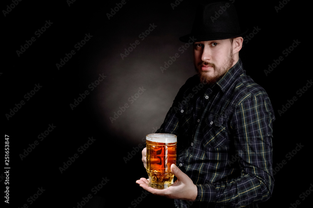 bearded man in a hat with a glass of beer on a black background