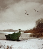 Green boat on the shore of a snow-covered lake