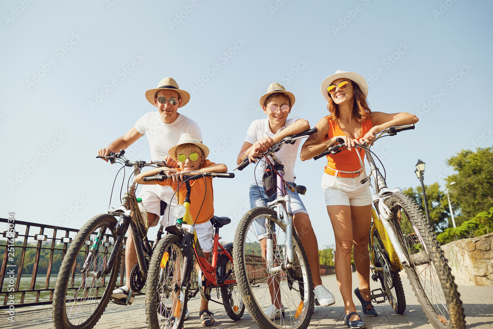 Obraz premium Cheerful family with bicycles standing on embankment