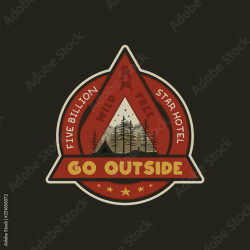 Hand drawn adventure logo with camp tent, mountains, pine trees forest and quote - Go outside, wild and free, five billion star hotel. Old style outdoors adventure emblem in retro style. Stock vector