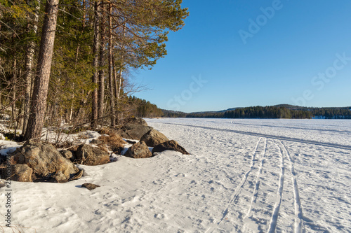 Winter day on a frozen lake with ski tracks in the snow. photo