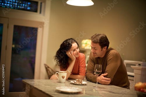 Mid-adult couple happily sitting and talking in their kitchen. photo