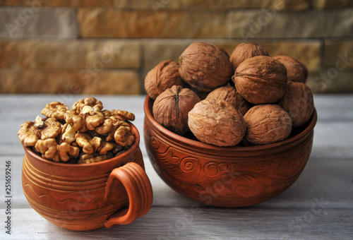 Walnut peeled and inshell in pottery on a white wooden table.