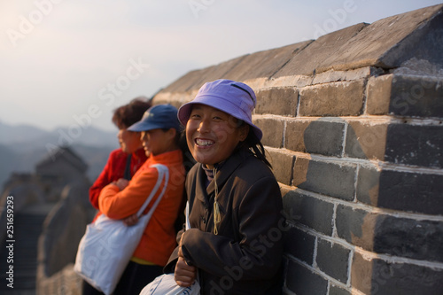 Three women huddled against a wall at the Great Wall Of China. photo