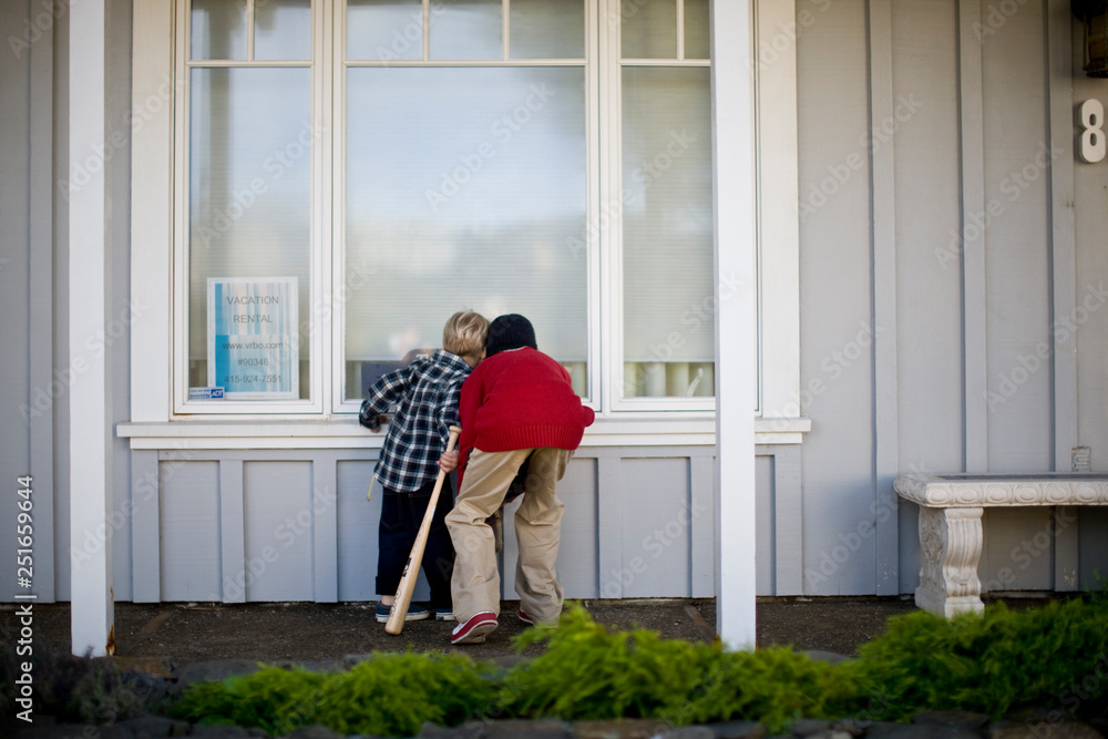 Two boys peering into window of an empty house Two boys peering into window of an empty house
