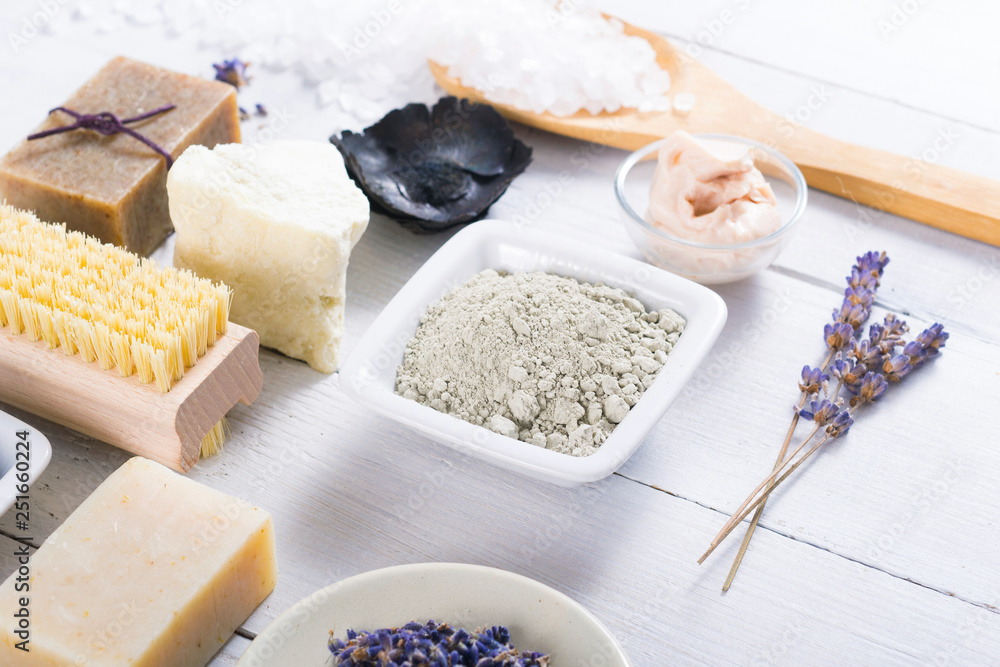spa massage mud and clay powder, soaps, bath salt, shea butter and lavenders on white wood table background spa massage mud and clay powder, soaps, bath salt, shea butter and lavenders on white wood table background