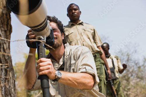 Young adult man using a camera with two mid-adult military men. photo