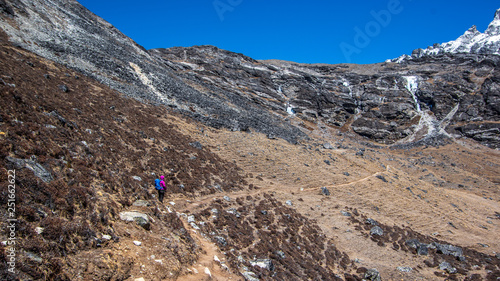 Landscape view of one female alpinist standing on the track leading to Kongma La pass. Sagarmatha (Everest) National Park, Nepal.