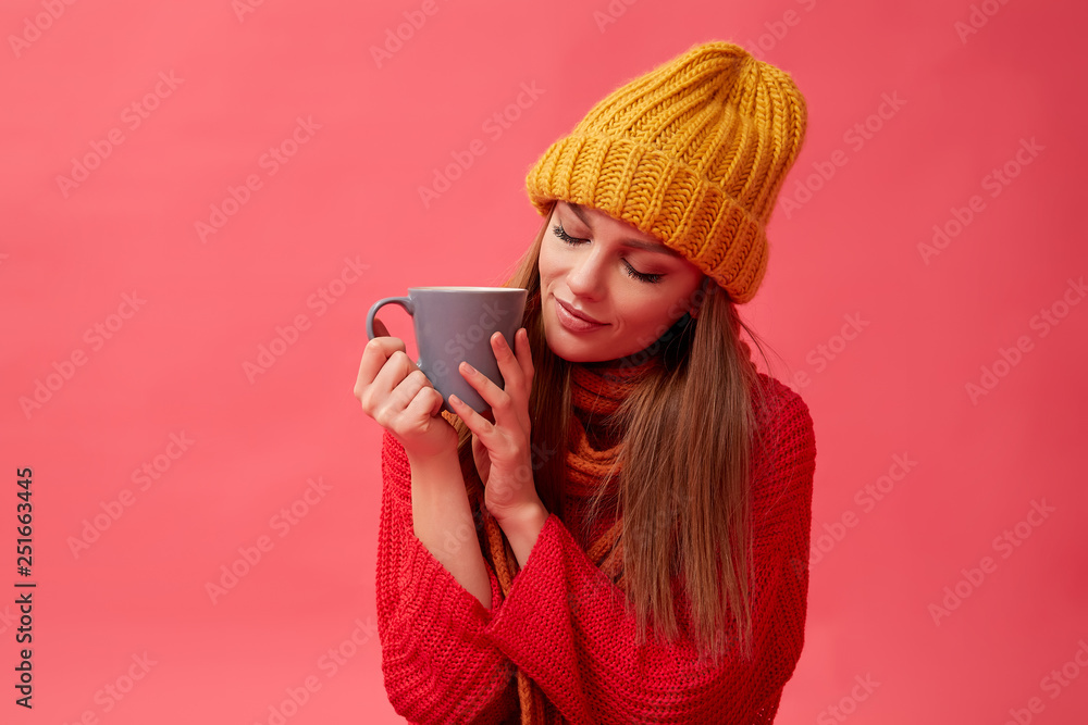 Beautiful teenage girl in warm cozy sweater with cup of hot drink. Red background. Studio Beautiful teenage girl in warm cozy sweater with cup of hot drink. Red background. Studio
