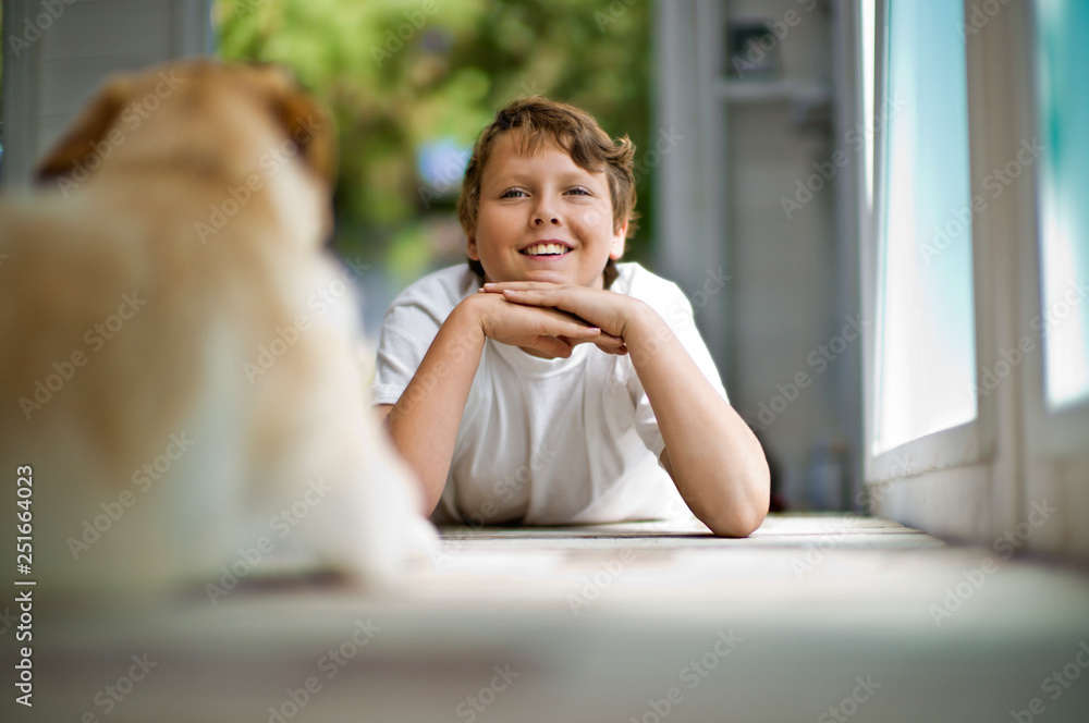 Smiling teenage boy daydreaming while lying down on a hardwood floor with his dog. Smiling teenage boy daydreaming while lying down on a hardwood floor with his dog.