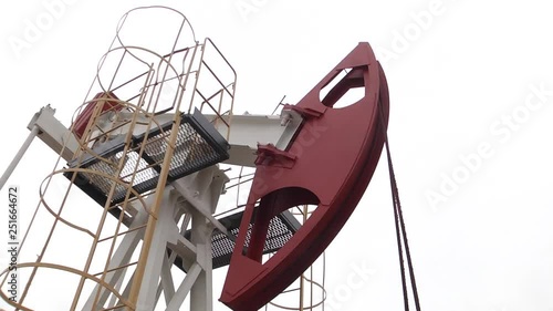 The pumping unit as the oil pump installed on a well. Equipment of oil fields. Operating oil and gas well, in remote field. The pumping unit as the oil pump installed on a well. photo