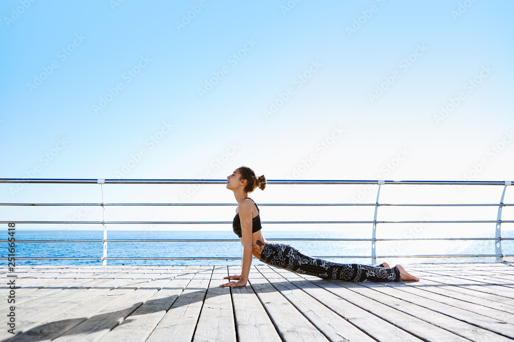 Side view of focused young beautiful slim woman practicing yoga by the beach. Side view of focused young beautiful slim woman practicing yoga by the beach.