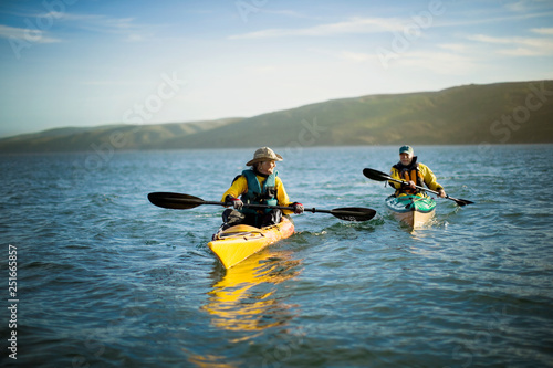 Happy senior couple kayaking together in the ocean on a sunny day.