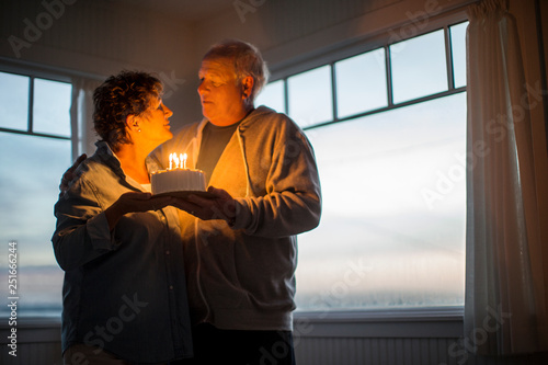 Happy senior couple celebrating a birthday with a birthday cake. photo