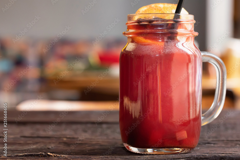 Close up glass jar with hot mulled wine and straw on dark wooden table Close up glass jar with hot mulled wine and straw on dark wooden table