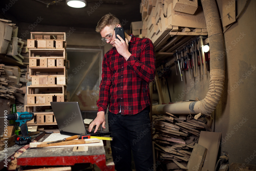 Naklejka premium Carpenter using laptop in workshop