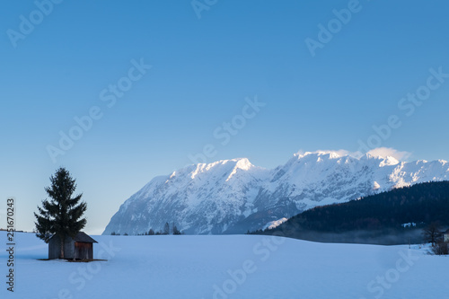 Snow covered hut on field with mountains Grimming, Schartenspitze, Steinfeldspitze