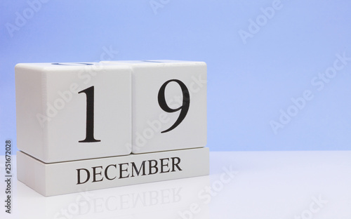 December 19st. Day 19 of month, daily calendar on white table with reflection, with light blue background. Winter time, empty space for text photo