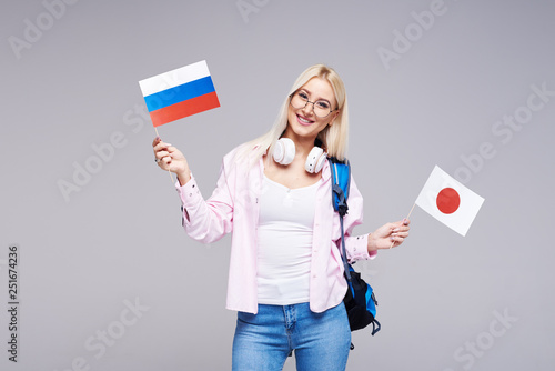 Education  foreign language translator  english  student - smiling blond woman in headphones holding Russia and Japan flags. Distance learning