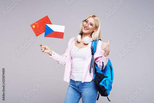 Education  foreign language translator  english  student - smiling blond woman in headphones holding China and Czech Republic flags. Distance learning. Shows a hand to the right  copy space for text.