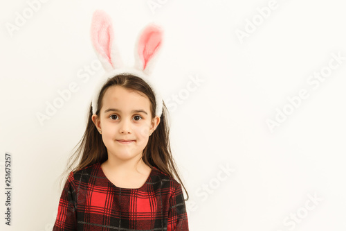 Surprised little girl wearing bunny ears, lying on light on Easter Holiday.