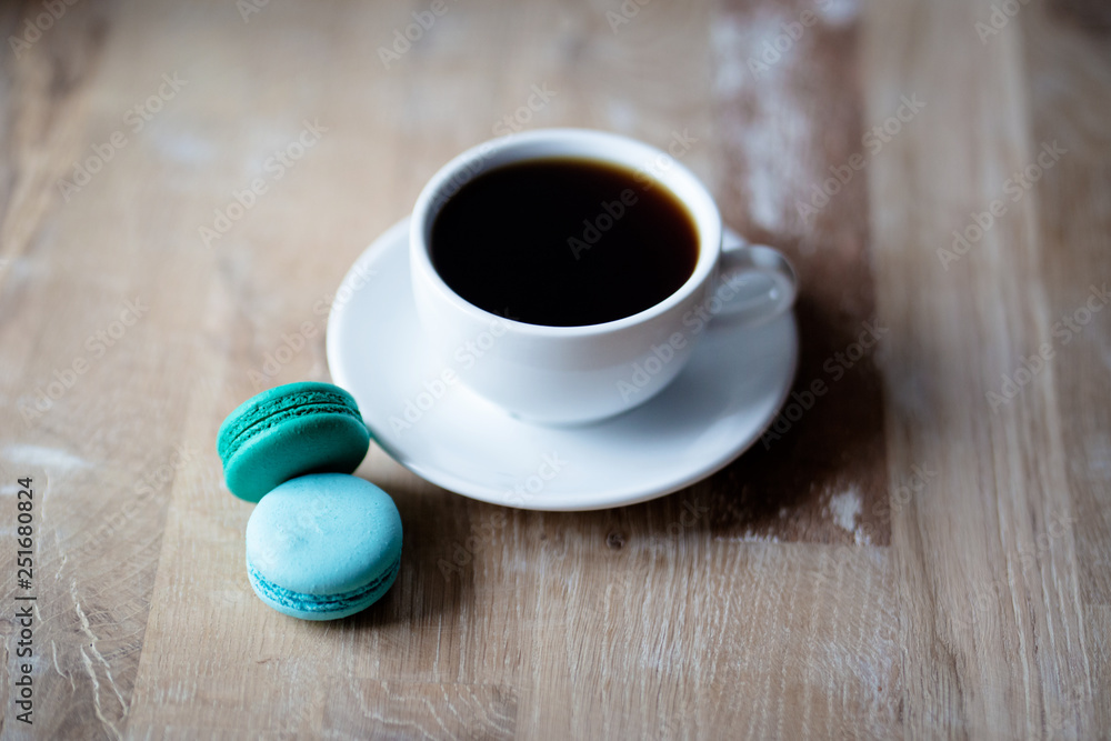 Good morning or Have a nice day message concept - white cup of coffee with colourful French macaroons on rustic wooden background Good morning or Have a nice day message concept - white cup of coffee with colourful French macaroons on rustic wooden background