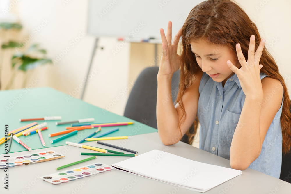 Young female pupil expressing panic, holding hands near head at classroom. Young female pupil expressing panic, holding hands near head at classroom.