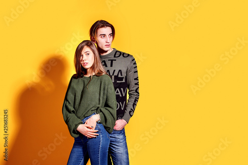 Couple in casual clothes posing in jeans type commercial fashion style on yellow wall