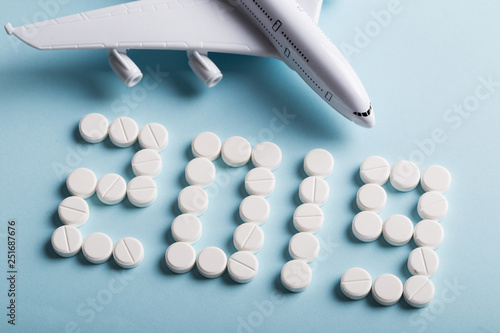 Assorted pharmaceutical medicine pills, tablets and capsules in office. Plane and 2019 year and blue background. photo