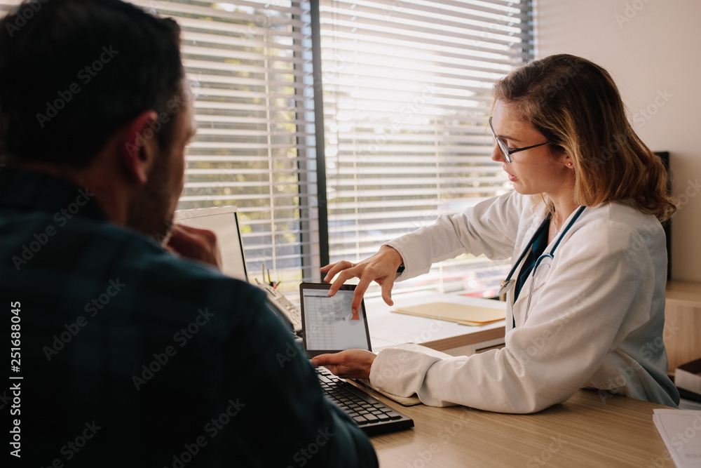 Doctor showing test results on tablet to her patient Doctor showing test results on tablet to her patient