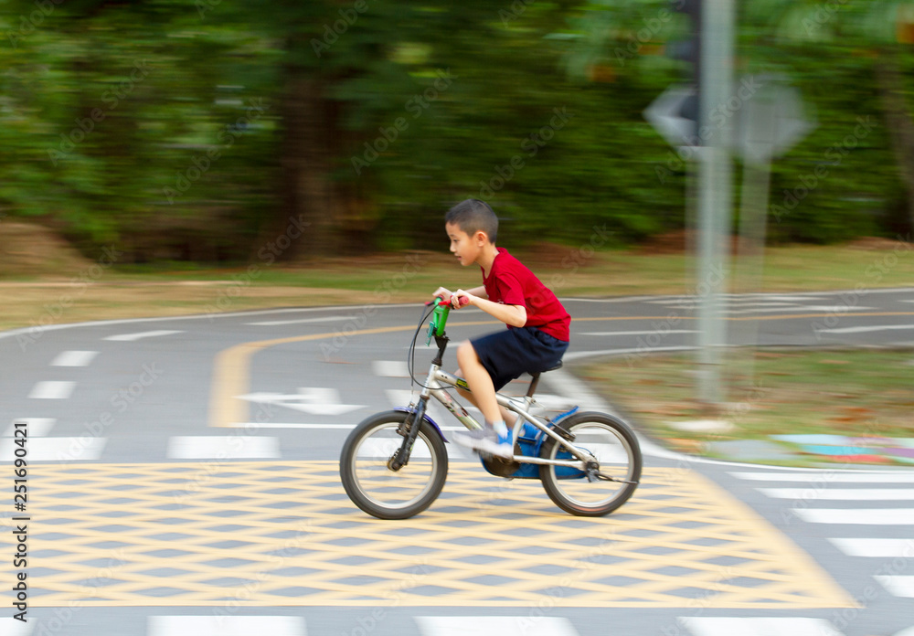 Asian boy riding bicycle in the park (motion blurred) Asian boy riding bicycle in the park (motion blurred)